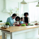 Happy multinational family with kids prepare vegetable salad in kitchen