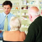 Pharmacist in pharmacy with senior couple